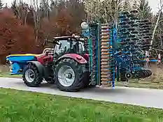 Roter Traktor der Marke Case mit Mähgerät auf einer Straße